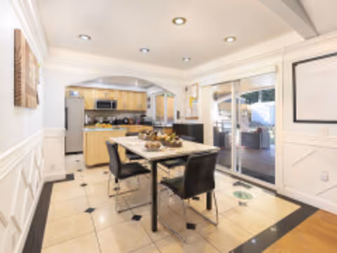 A bright dining area in a senior living facility with a table and kitchen in background.