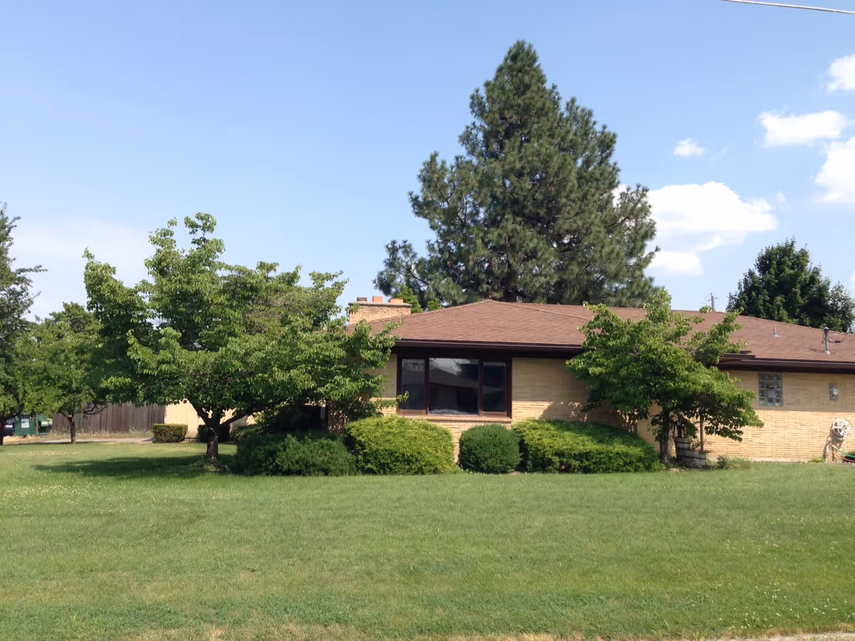 Exterior view of a single-story brick building with a large front window and green lawn.