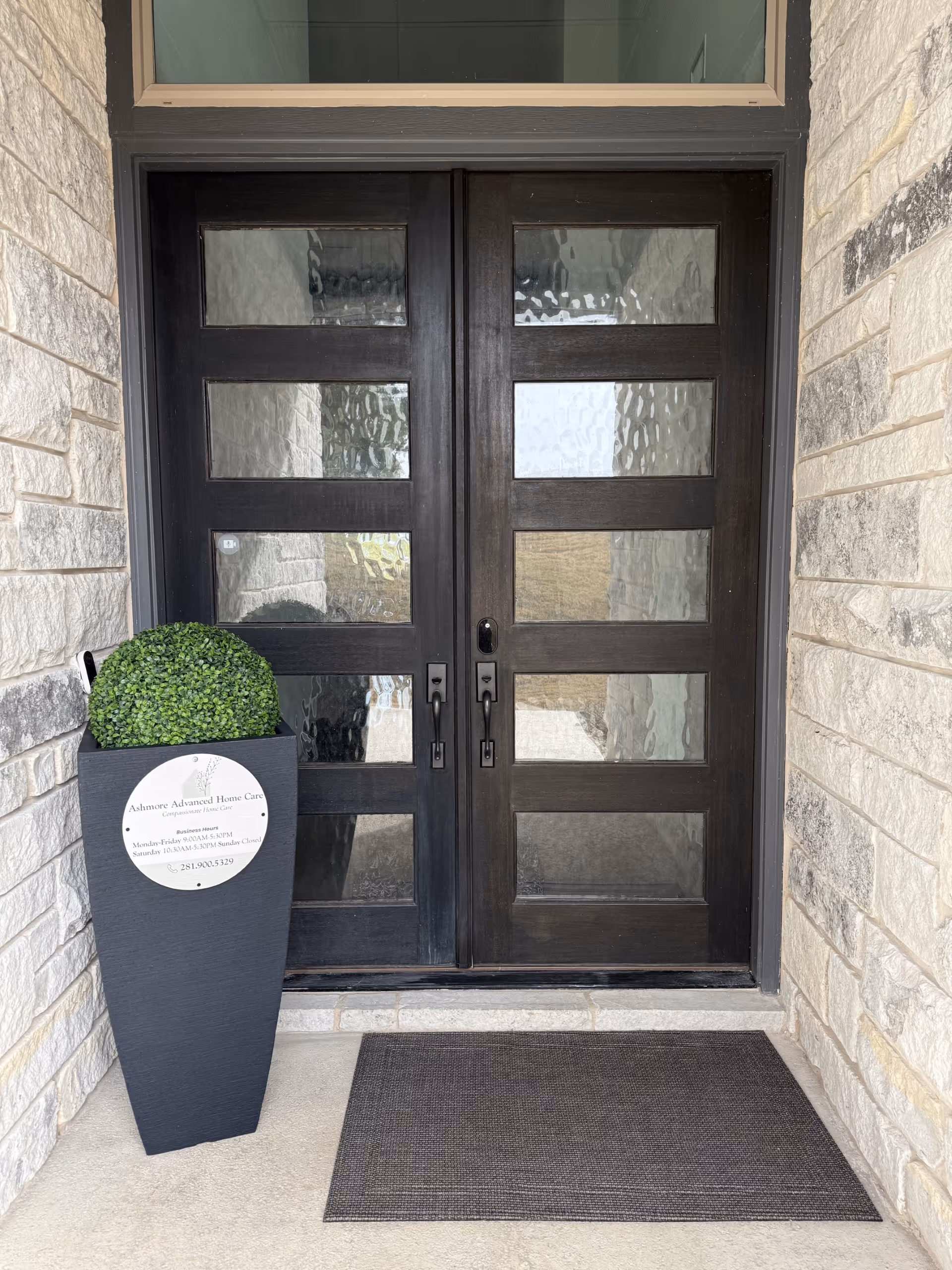 Double front doors with glass panels, surrounded by stone walls and a planter.