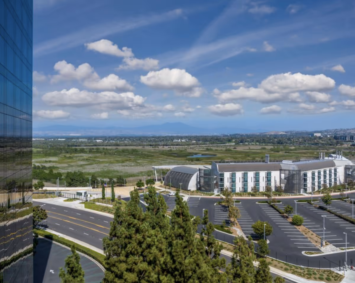 A modern Cognitiva Care building, glass facade, and expansive parking lot under a blue sky.