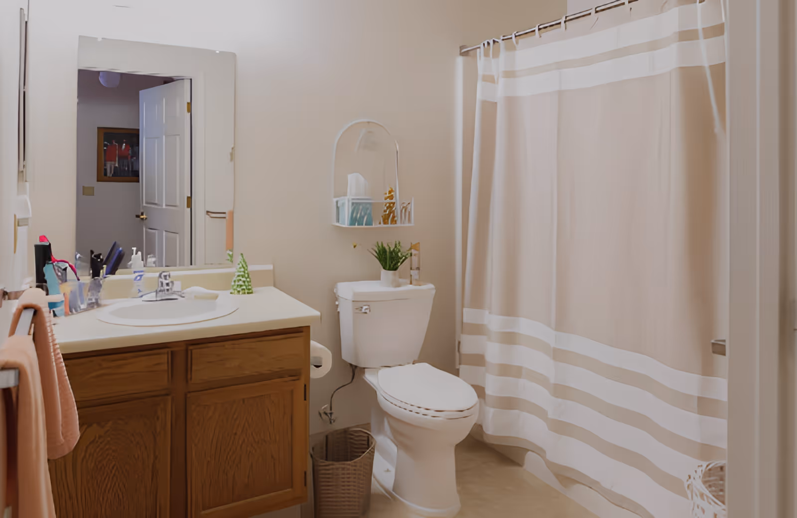 Small residential bathroom with a sink vanity, toilet, and a beige striped shower curtain.
