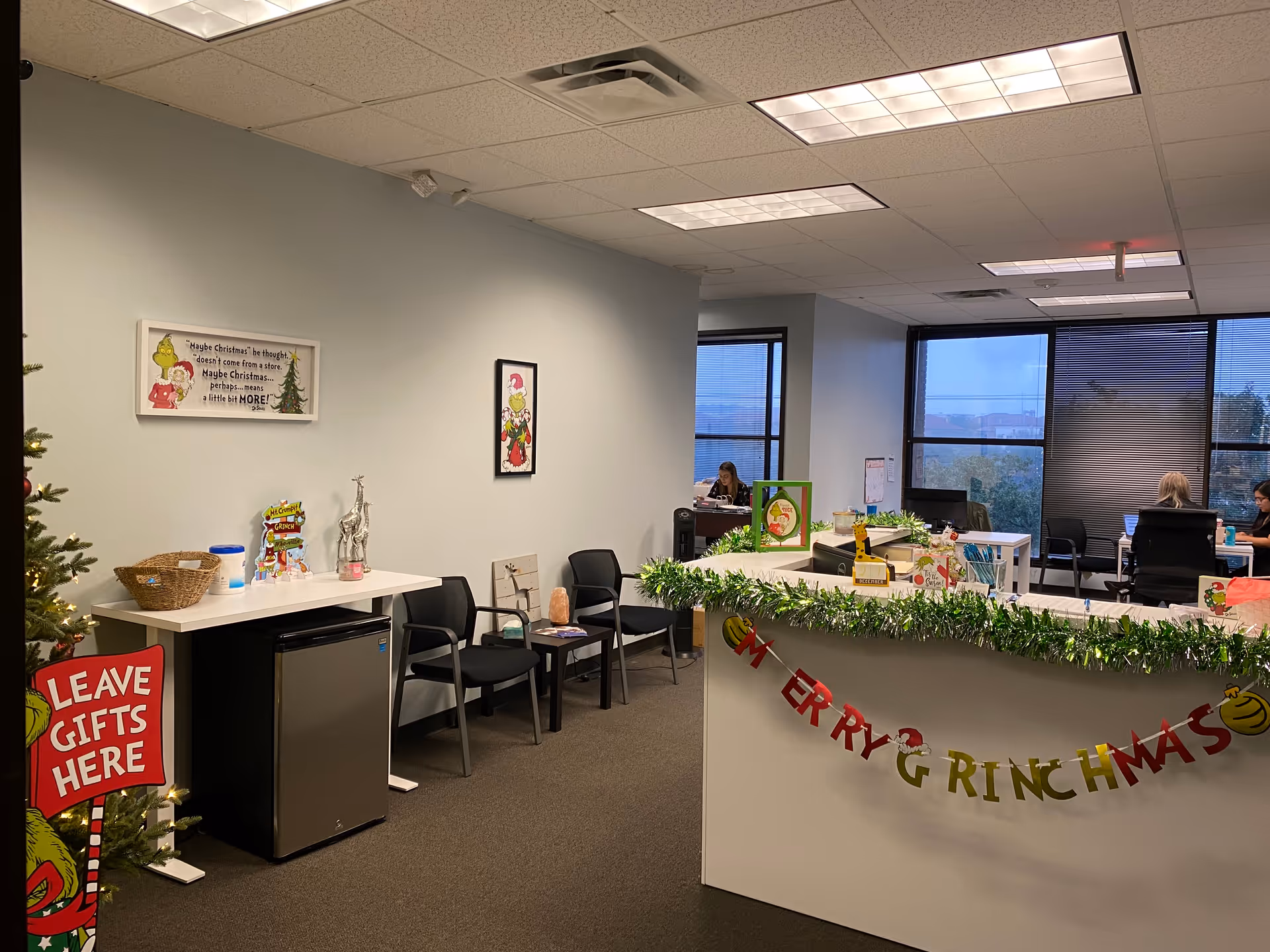 Reception area of a senior facility decorated for Christmas with garlands and staff at desks.