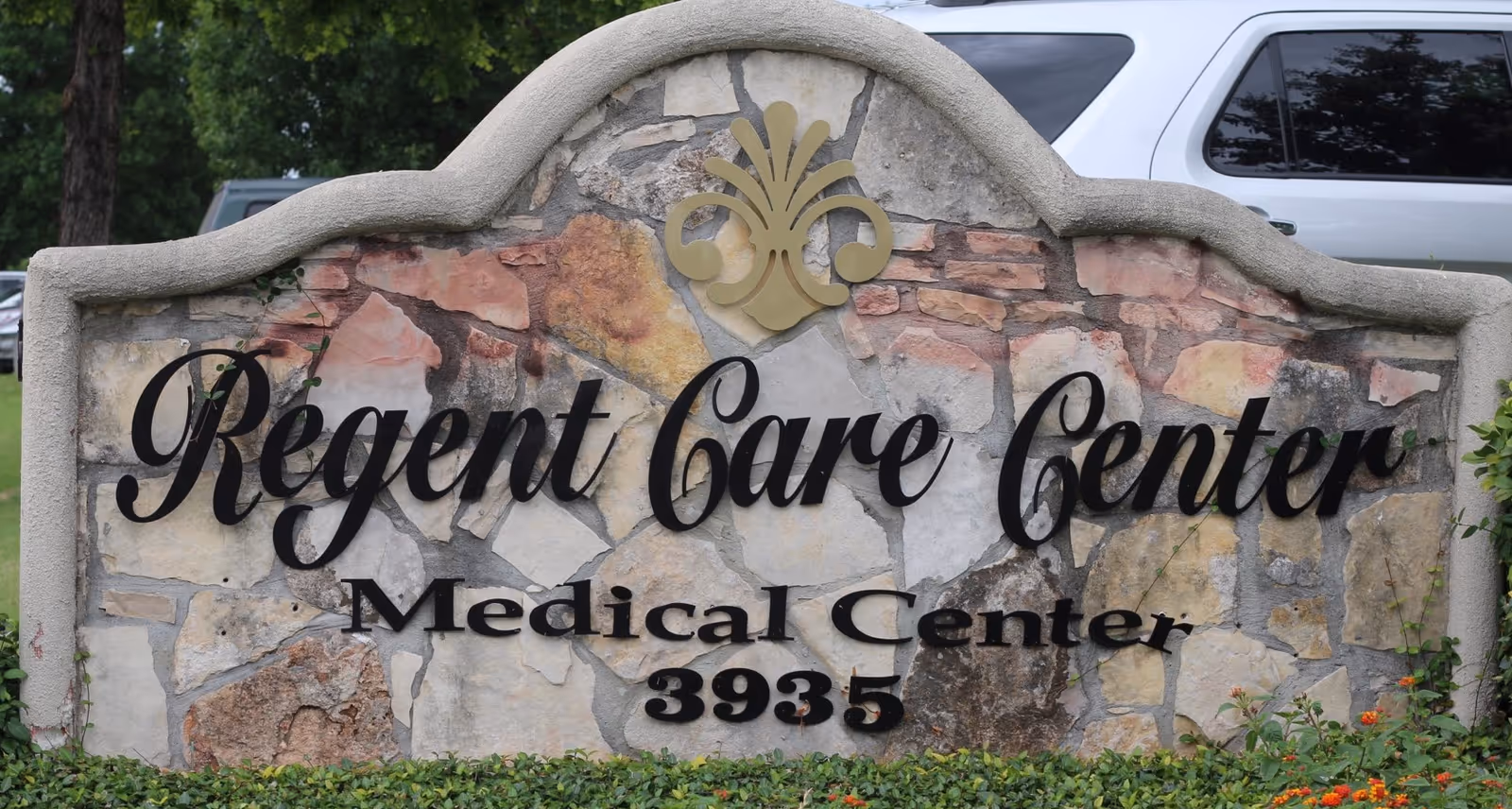 Stone exterior sign bearing Regent Care Center and Medical Center, 3935, set among shrubs.