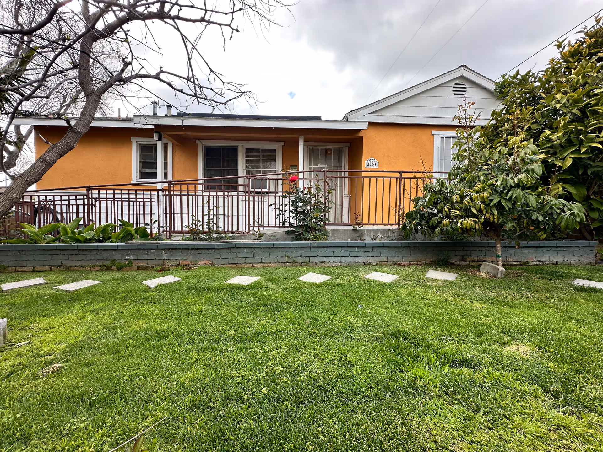Orange single-story facility facade with railing and lawn in front.