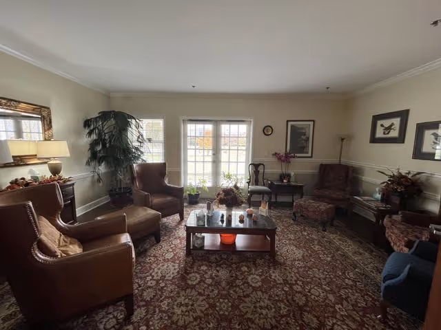 Sunlit Abbey Hospice living room with leather chairs, coffee table, and rug.