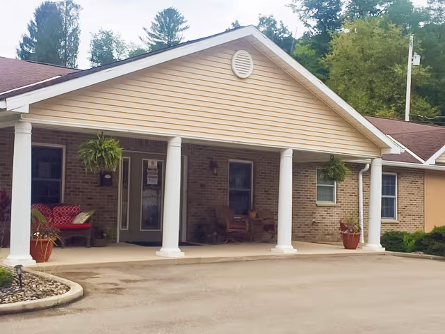 Front entrance of a brick senior living facility with columns and hanging planters.