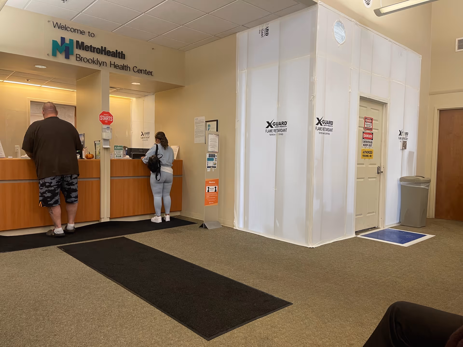 Welcome to MetroHealth Brooklyn Health Center reception with two visitors at the front desk.