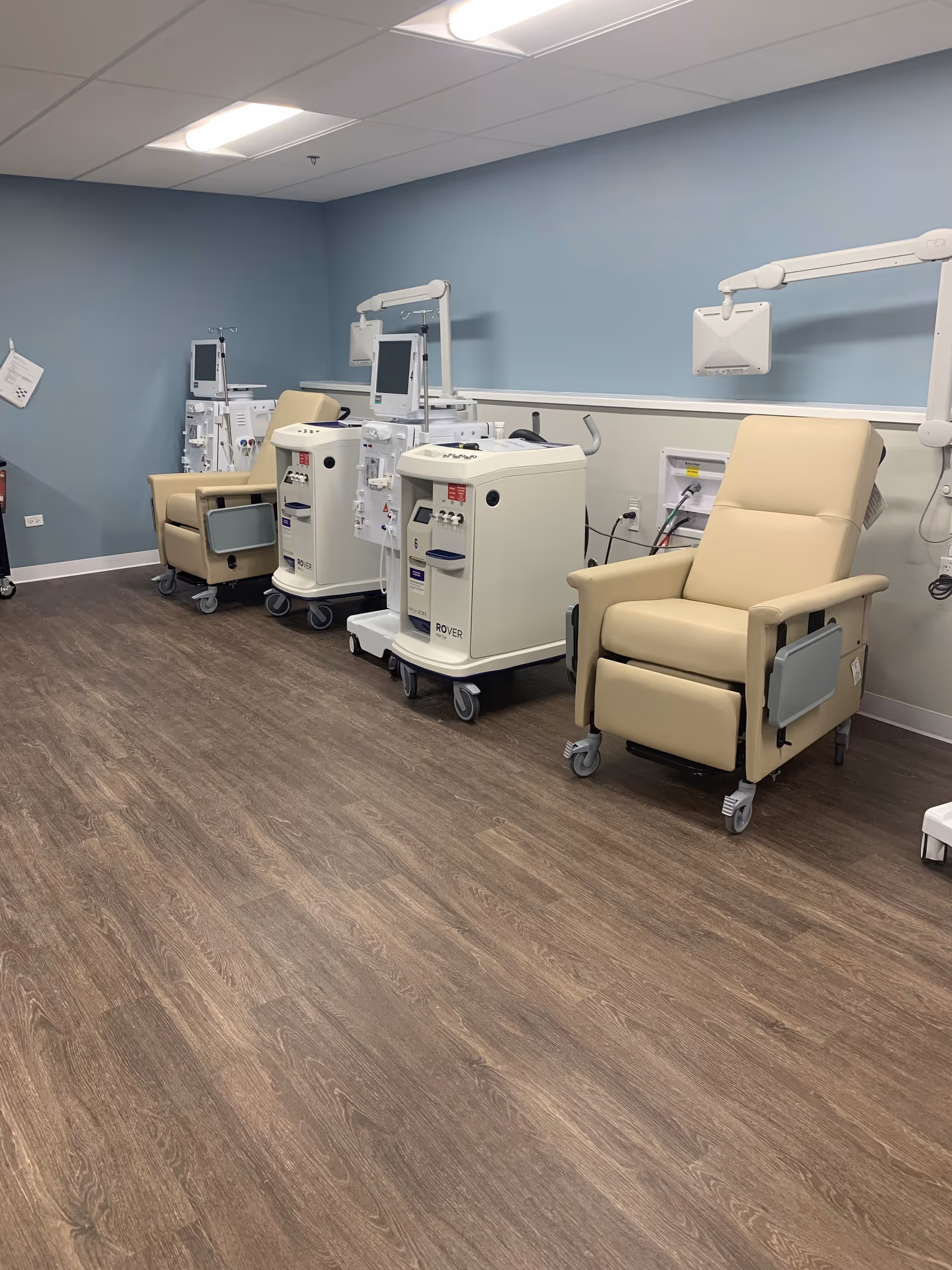 Clinical treatment chairs and medical monitors line a blue-walled interior room.