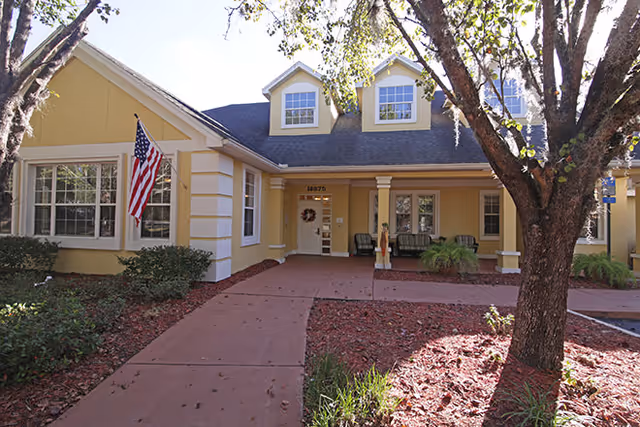 Exterior view of Brookdale Mandarin Central, a yellow building with front entrance and American flag.