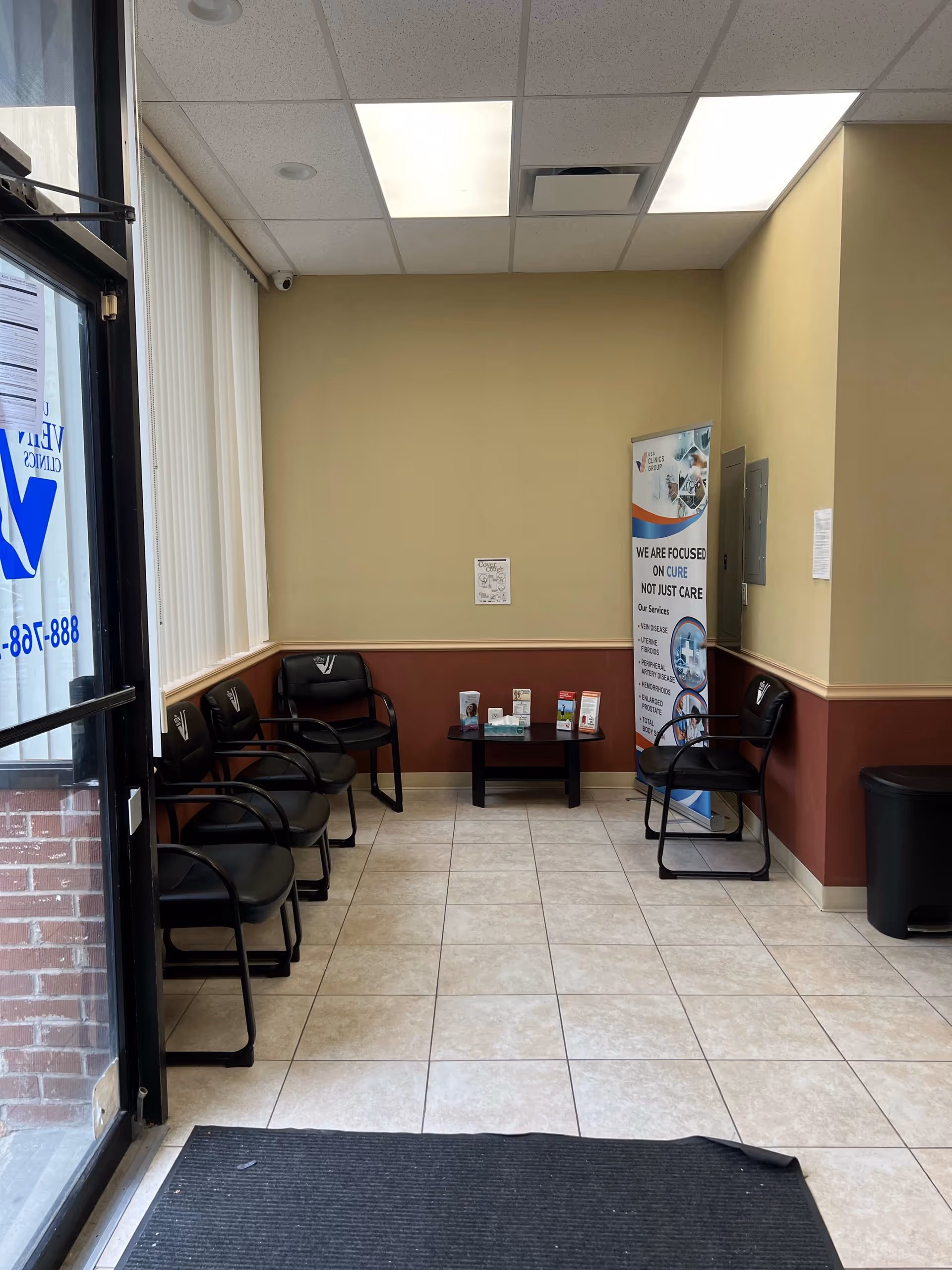 A small waiting area inside with black chairs, a brochure table, and a banner.