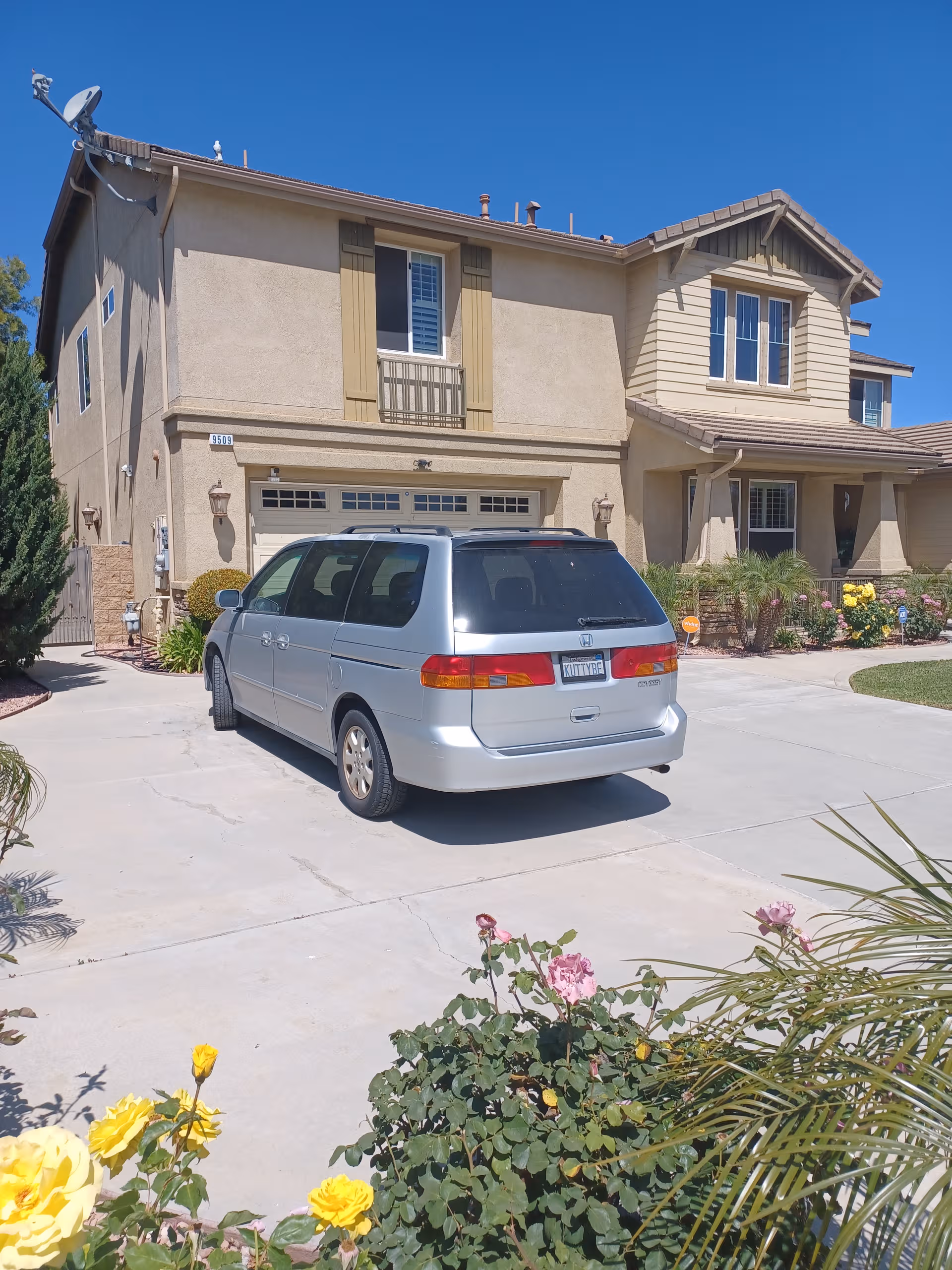 Two-story tan senior living home facade with a silver minivan in the driveway.
