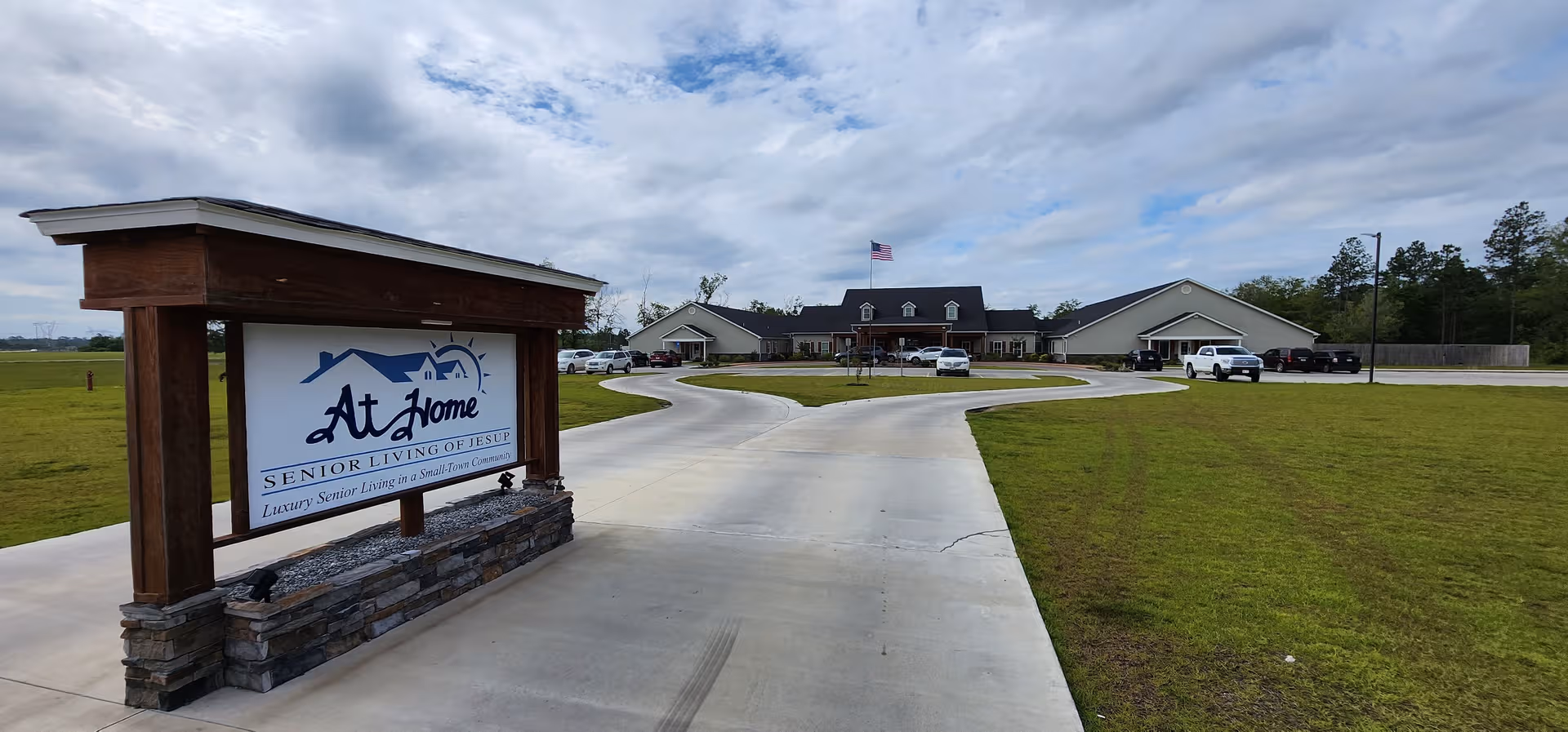 Exterior view of At Home Senior Living of Jesup with curved driveway and sign.