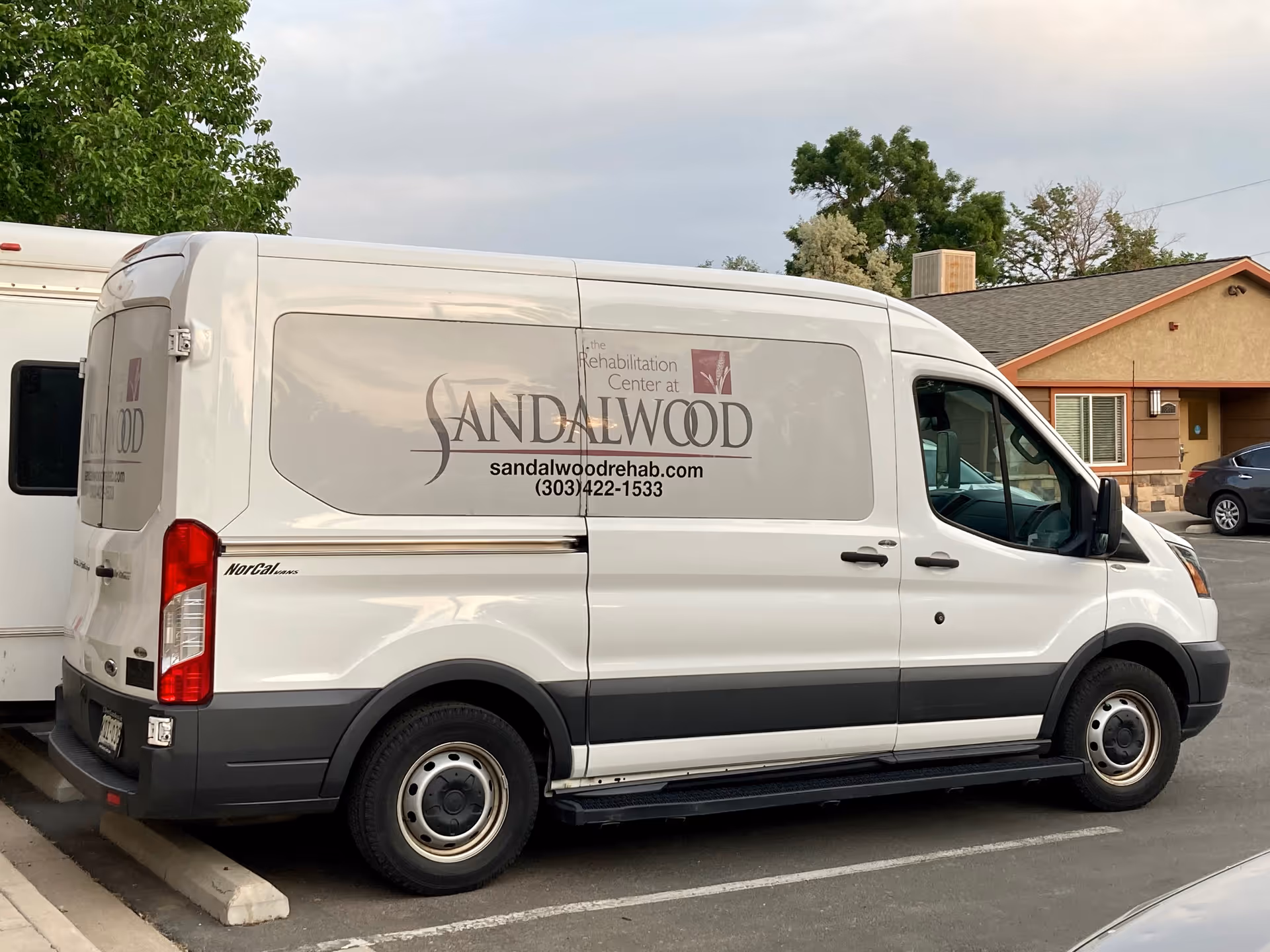 White Sandalwood Rehabilitation Center van parked in a lot by a building.