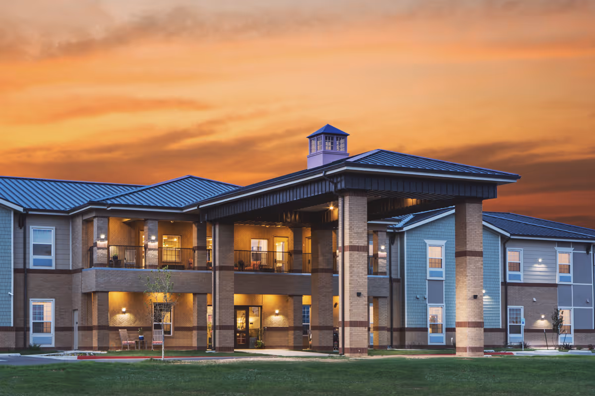 Exterior view of The Legacy at South Plains facility showing an illuminated entrance at dusk.