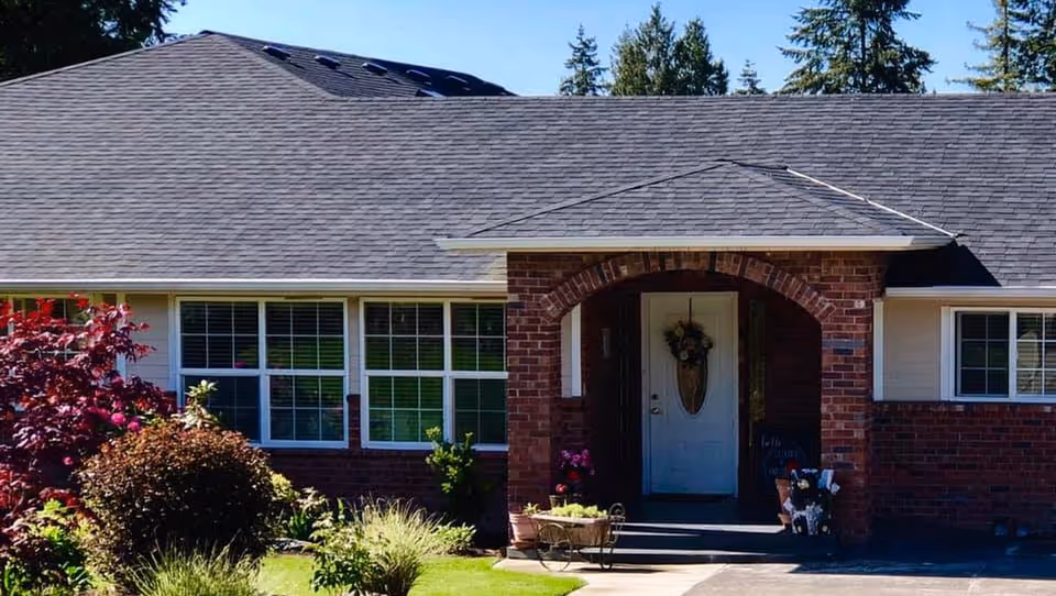 Front exterior of a single-story brick building with curved entry arch and plants.