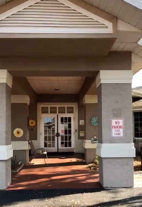 Front entrance of a senior living facility with double doors and decorative wall decor