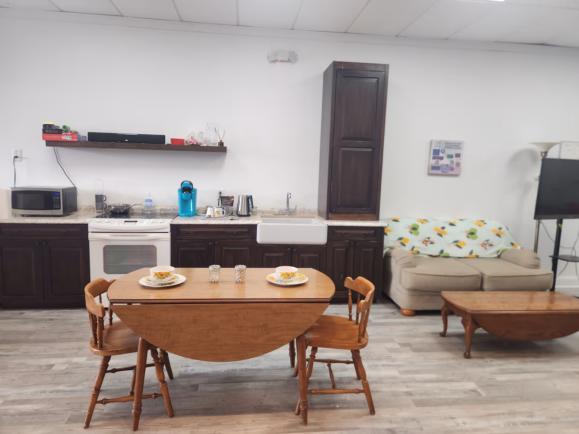 Open dining area with a wooden table set for meals, kitchen counters in background.