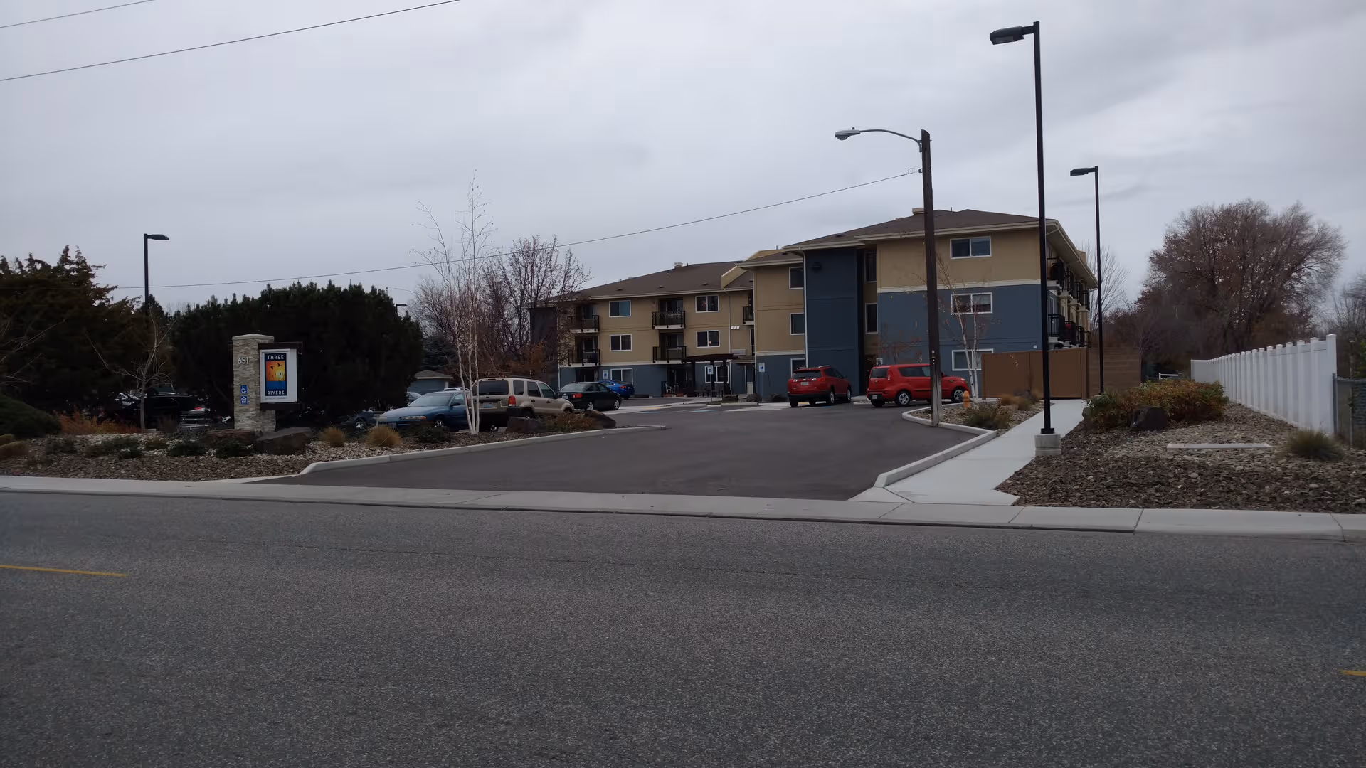 Exterior view of a multi-story retirement apartments building with a parking lot.