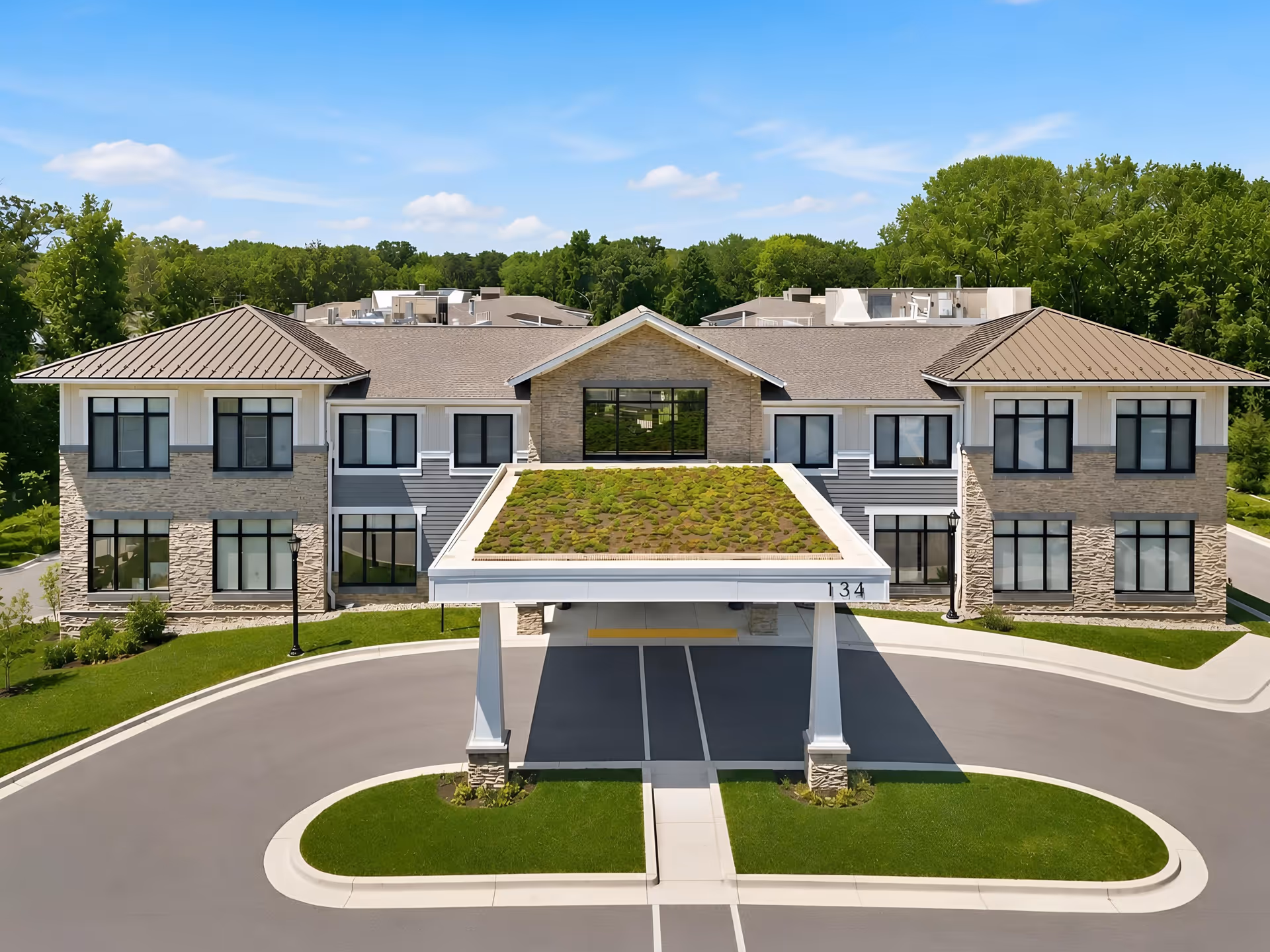 Two-story senior living building with a covered entrance, circular driveway, and landscaping.
