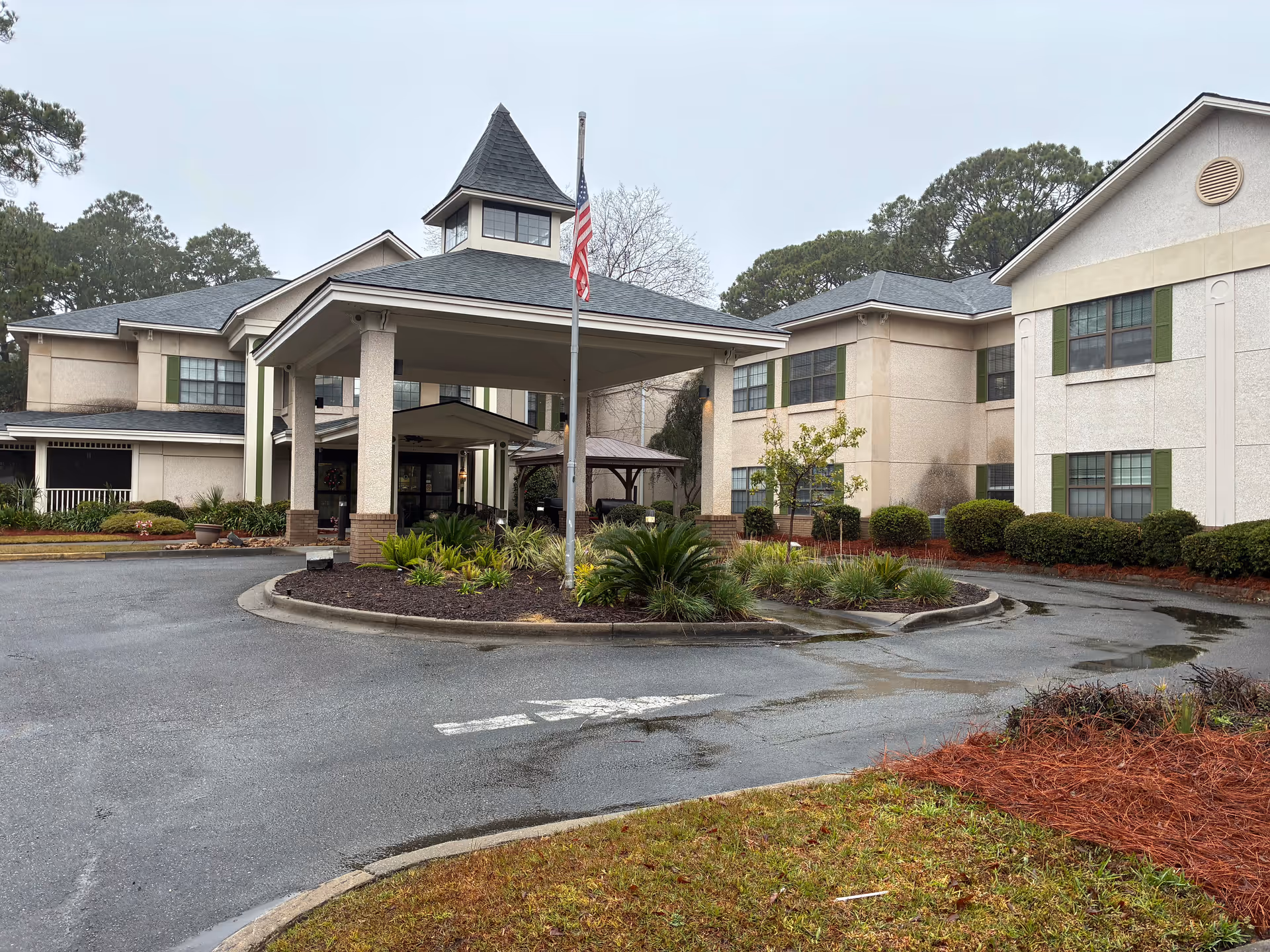 Exterior view of Oaks at Habersham facility with porte-cochere, flagpole, and landscaping.
