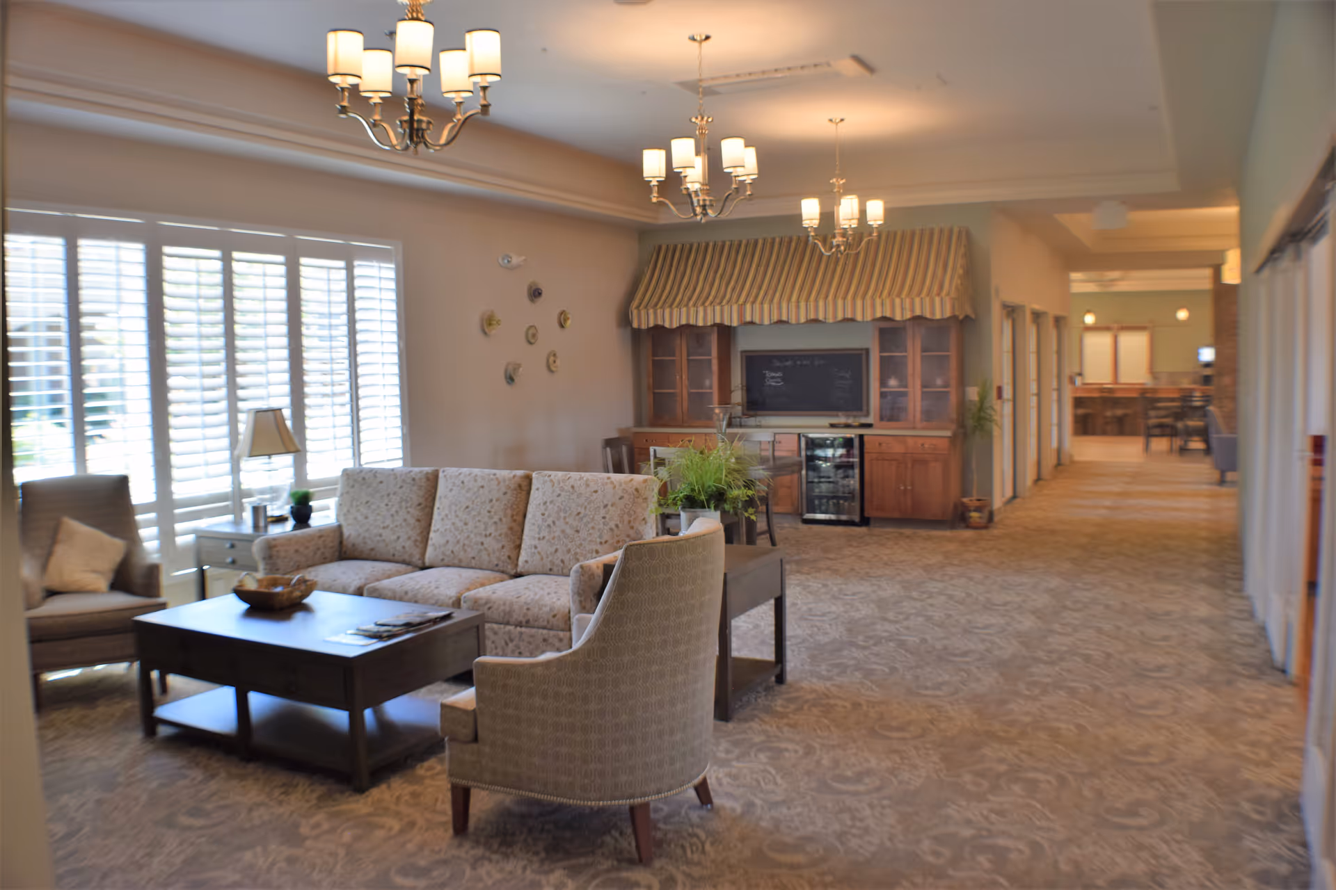 Bright lounge with sofas, chairs, coffee table, and striped canopy over a cabinet.