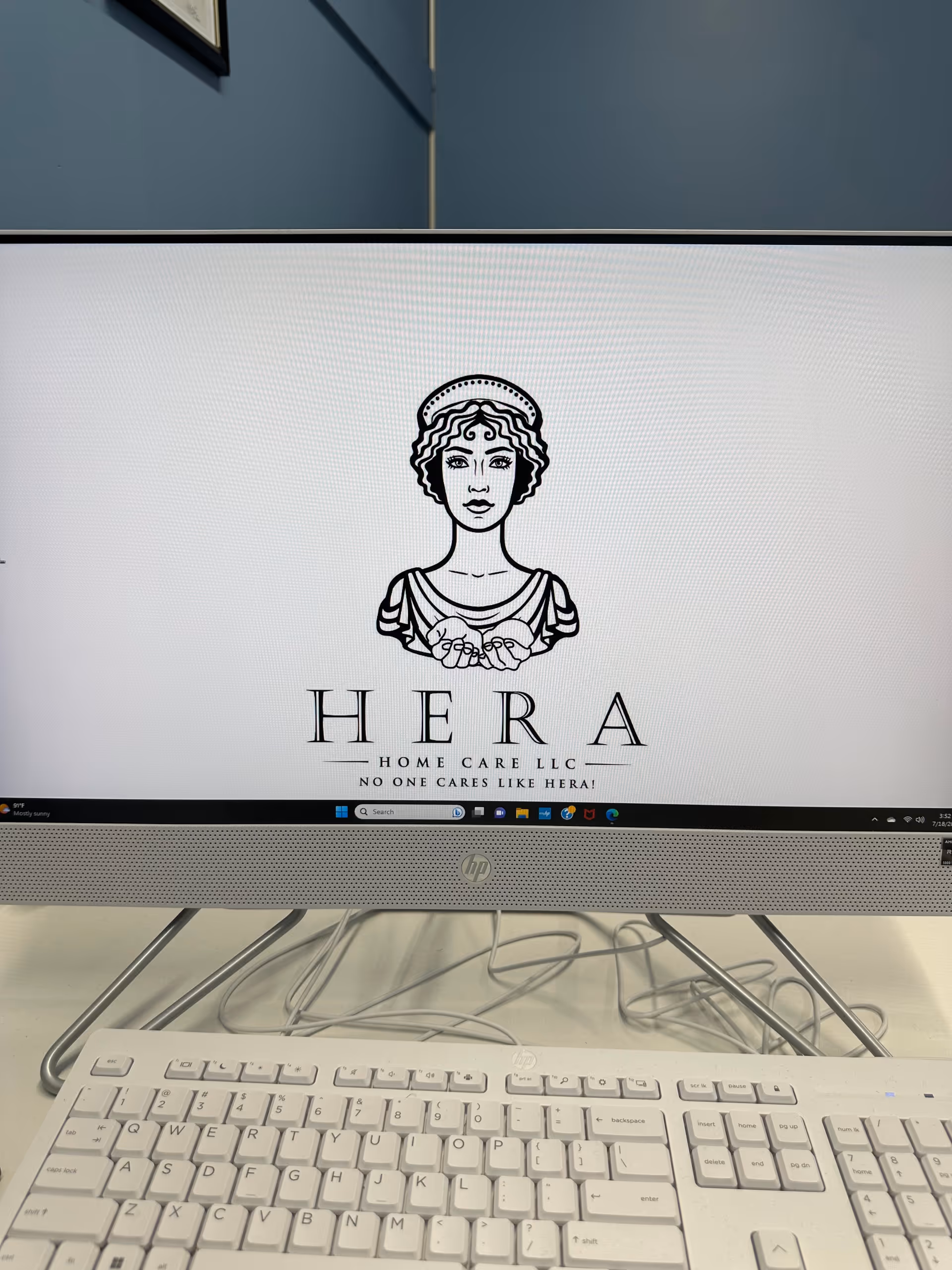 Monitor displays Hera Home Care LLC logo on a desk.