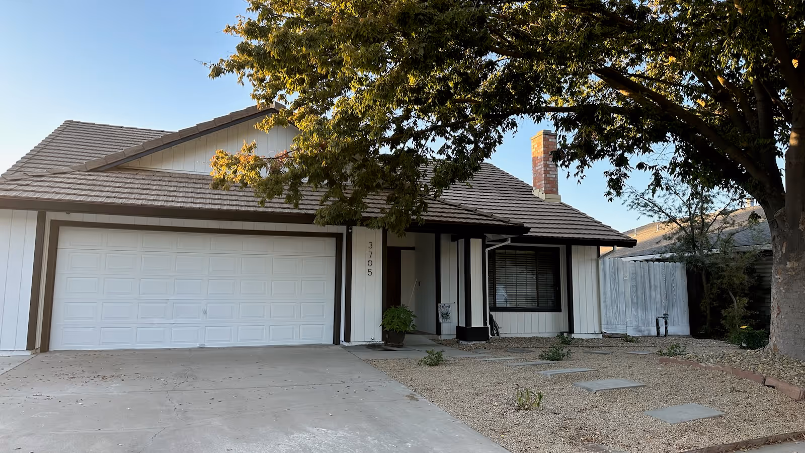Single-story RCFE building with a two-car garage, front yard, and large tree shade.