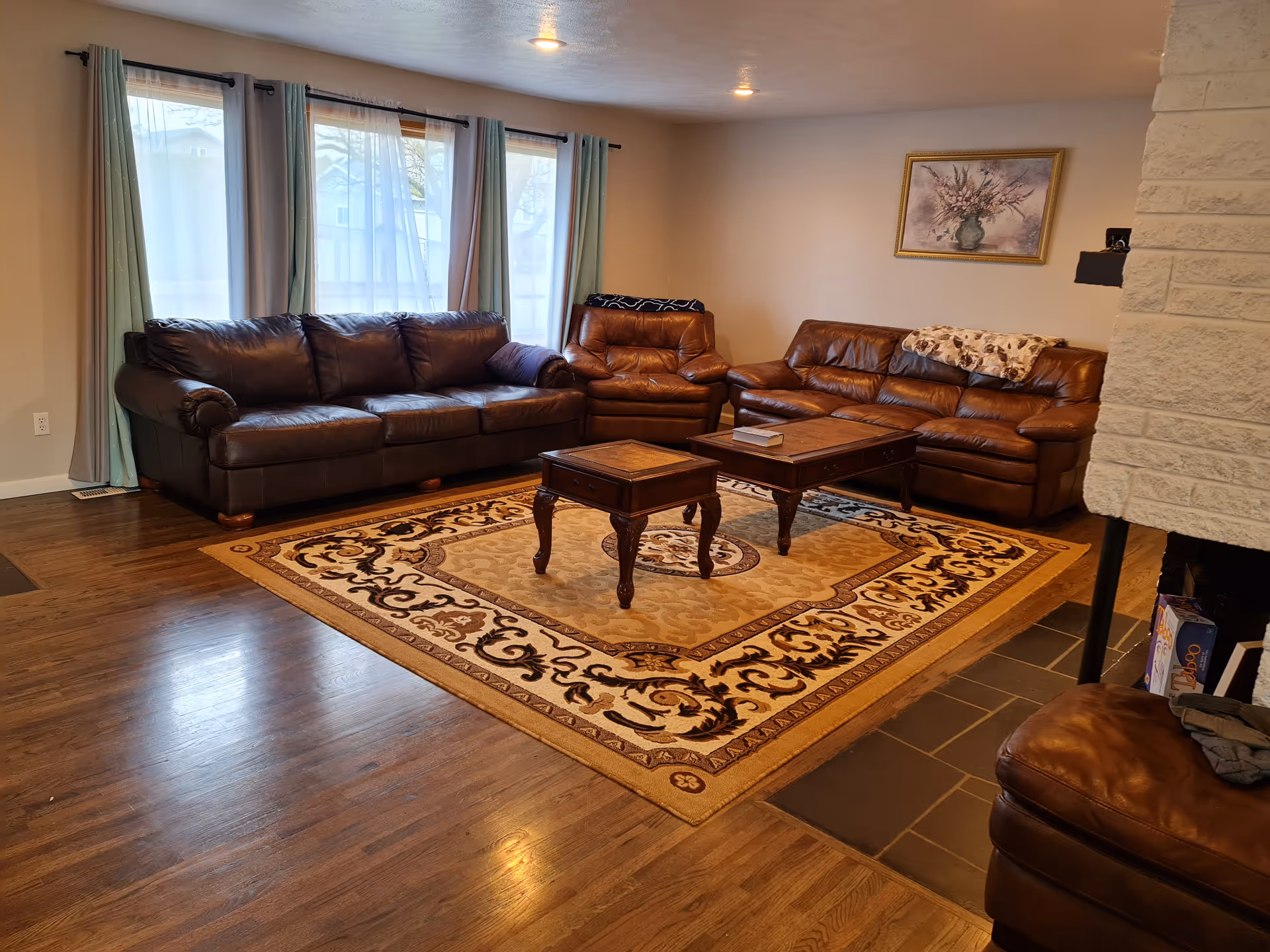 Cozy living room with brown leather sofas, two coffee tables, and a patterned rug.