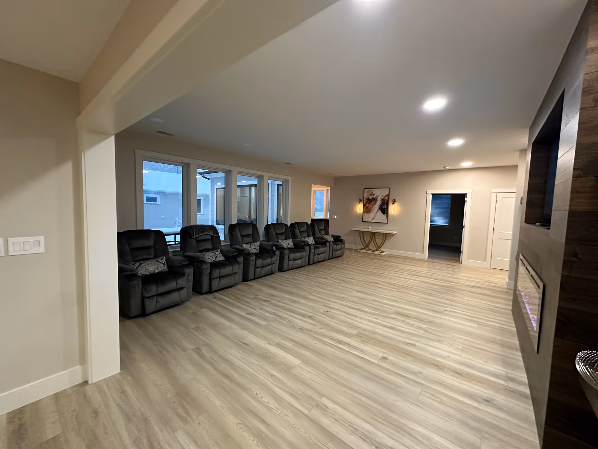Spacious senior living lounge with a row of black recliners along windows.