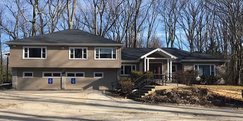 Modern senior living facility exterior with a front entrance, stairs, and a two-car garage.