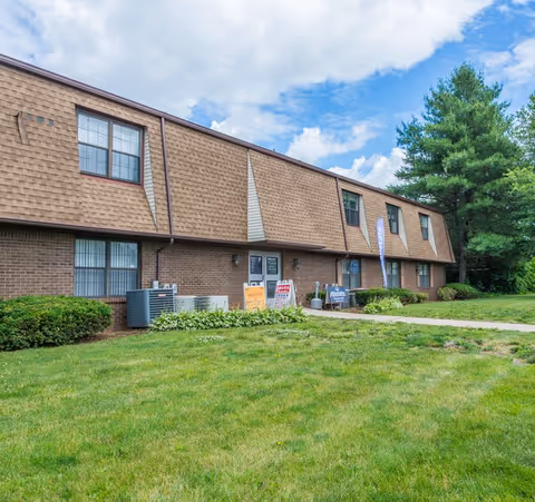 Brick senior living facility exterior with windows, signs, and a green lawn.