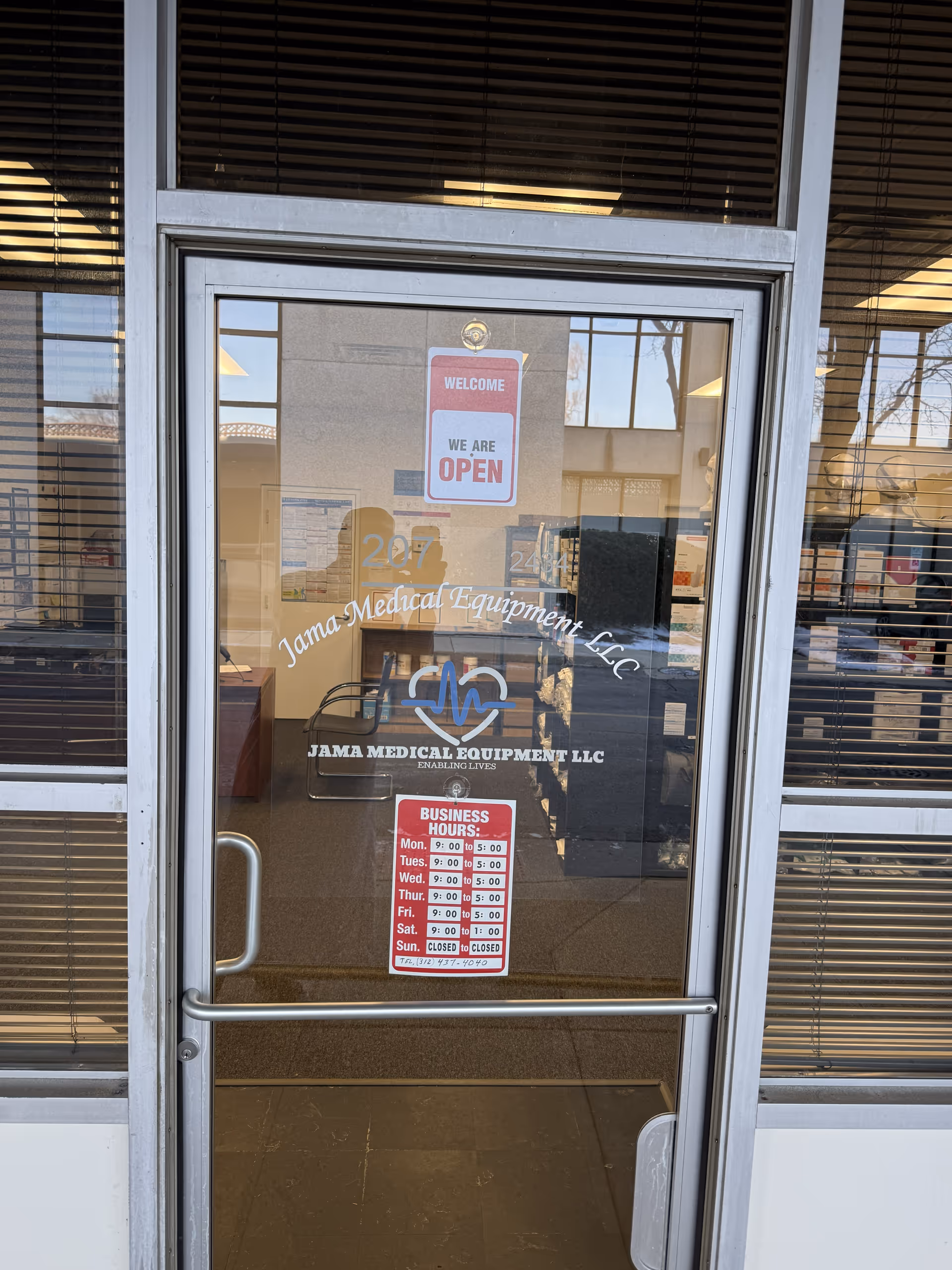 Glass entrance door with Jama Medical Equipment LLC logo and an open sign inside a lobby.