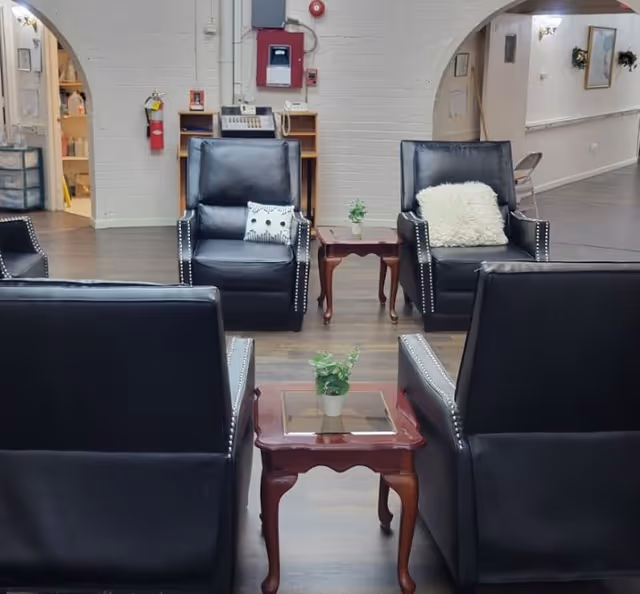 A cozy lobby seating area with black leather chairs and small wooden tables.
