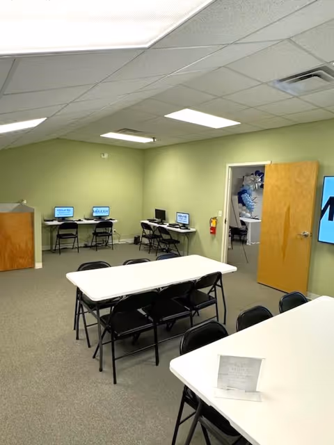 The light green-walled interior features tables, chairs, and several computer stations.