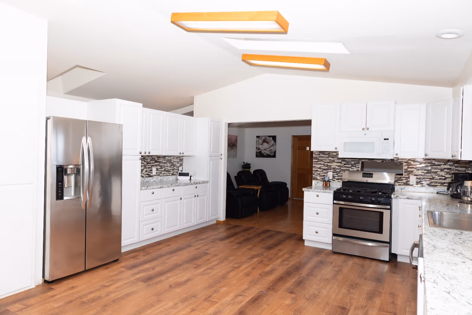 Bright kitchen with white cabinets, stainless steel appliances, and wood flooring.