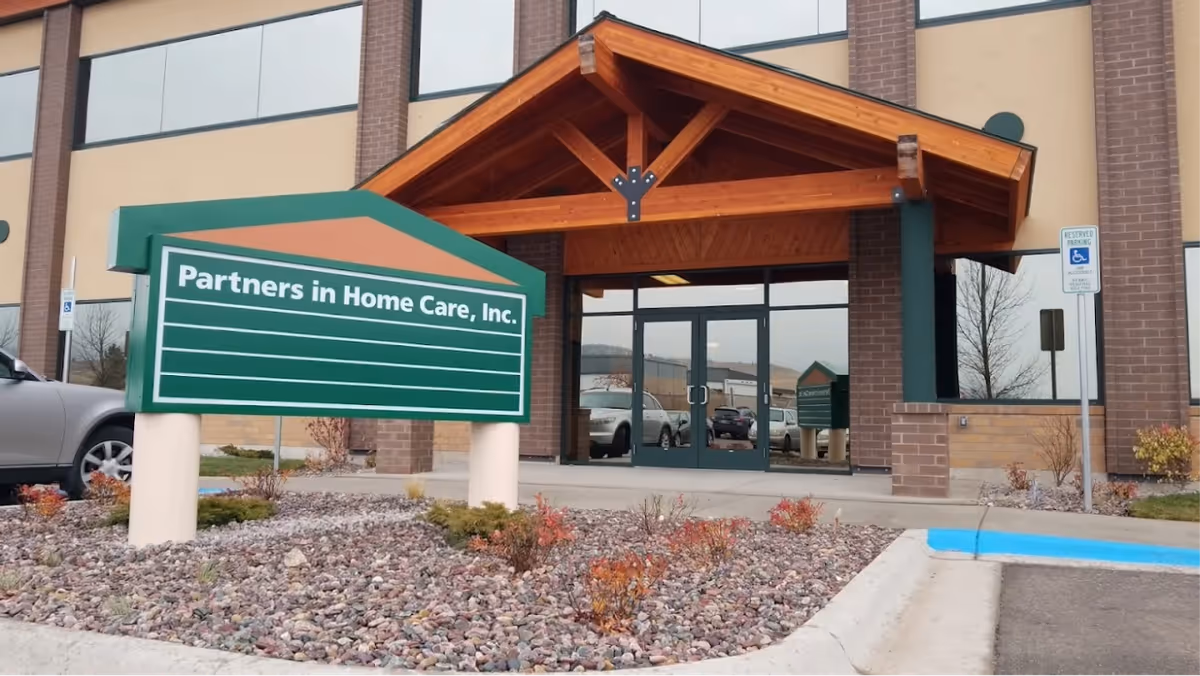 Exterior view of a Partners in Home Care entrance with a large green sign.