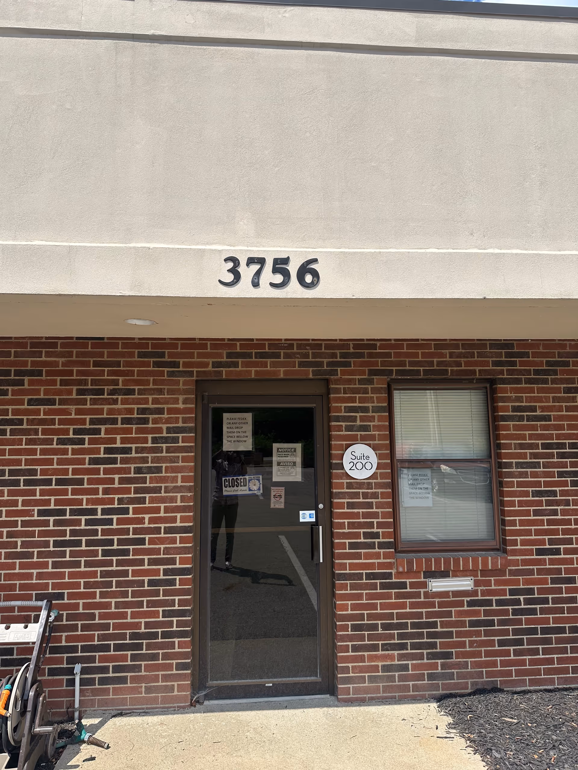 Exterior brick entrance with the number 3756 above glass door and window