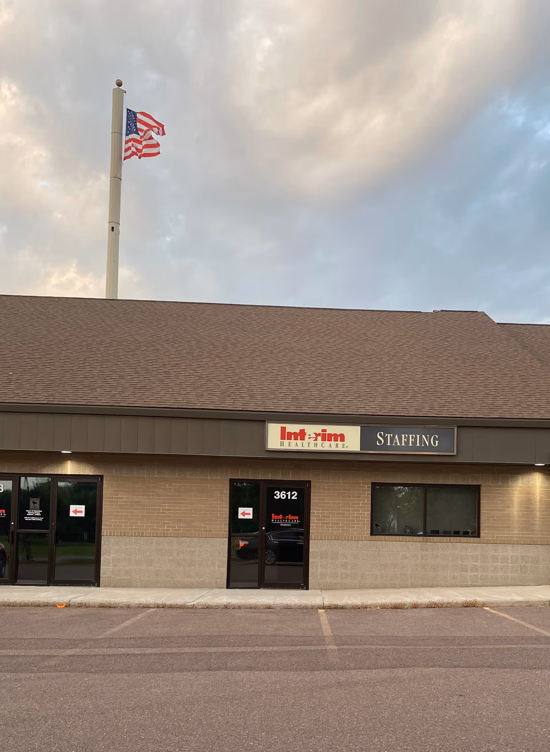 Exterior view of Interim HealthCare of Sioux Falls building with flag and Staffing sign.