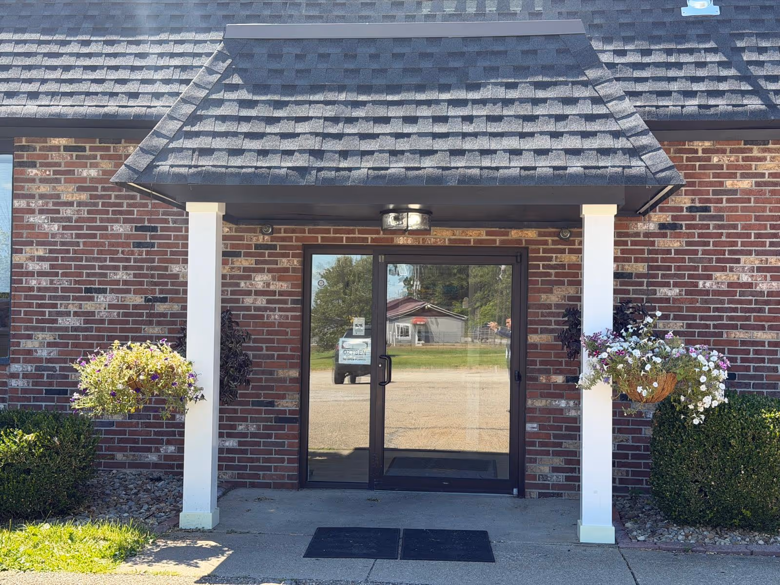 Brick building entrance at Astoria Place of Cambridge with glass doors and hanging baskets.