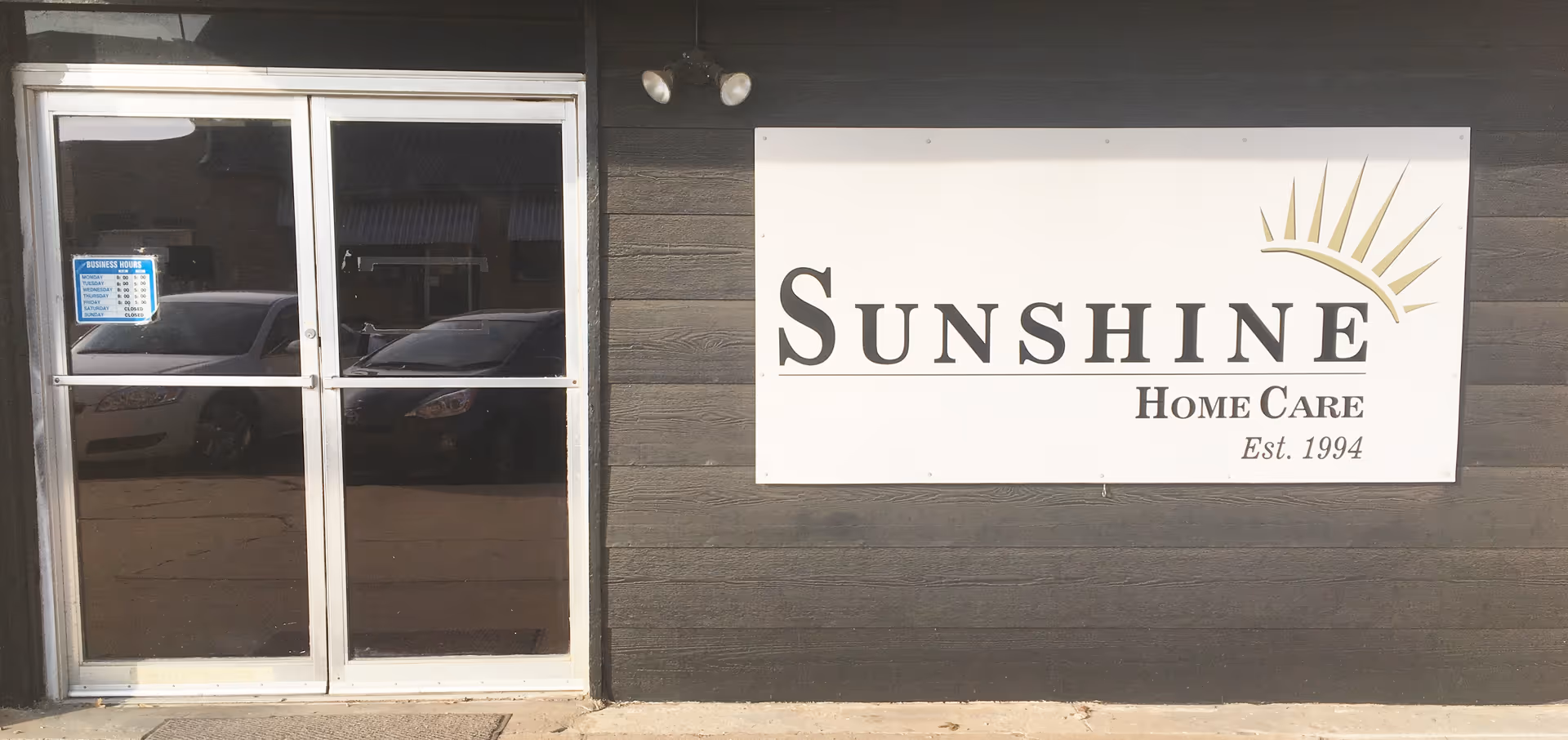 Front exterior of Sunshine Home Care building with glass entrance and sign.
