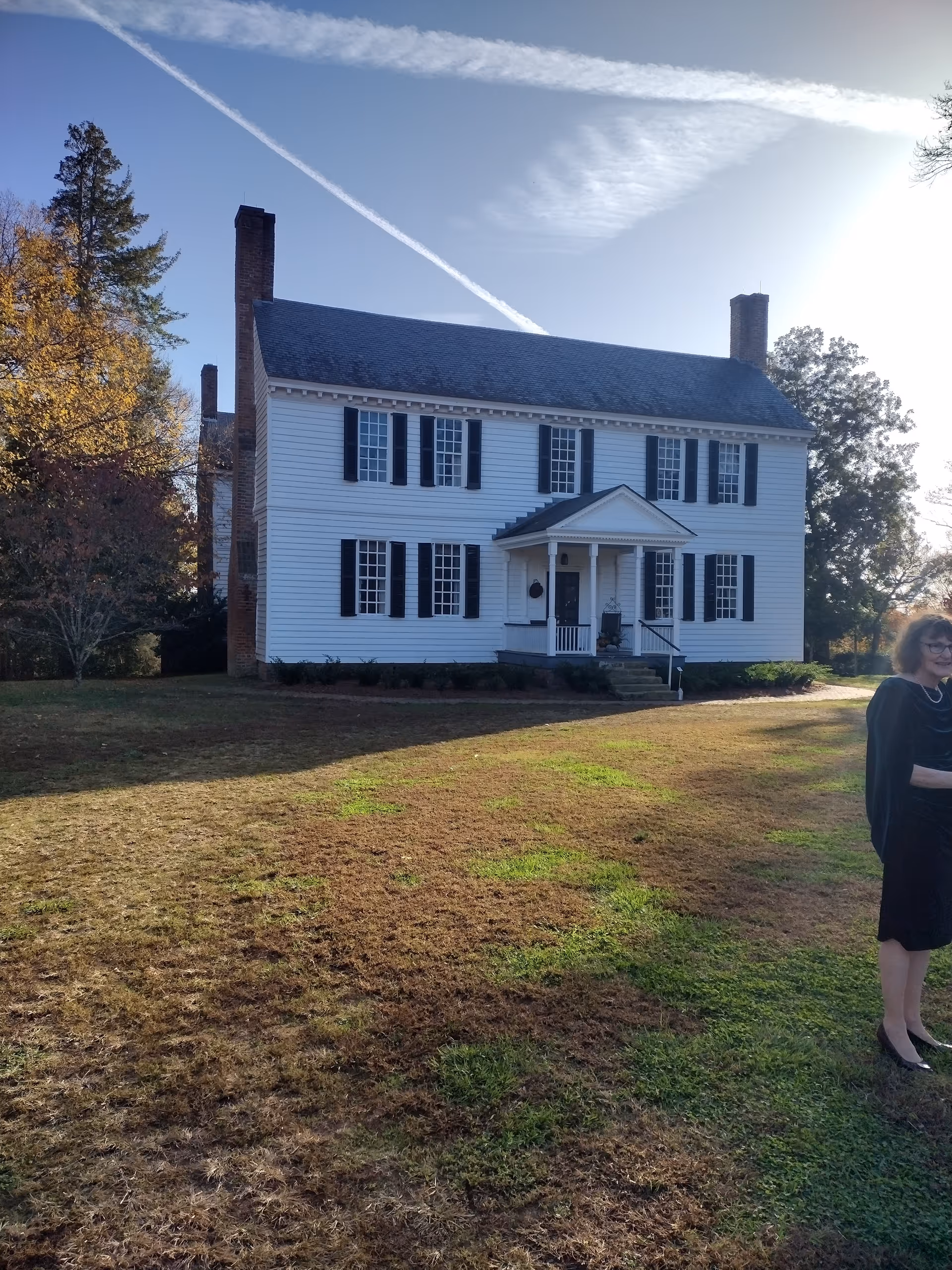 Front exterior of a white, two-story house facility with black shutters and a front porch.