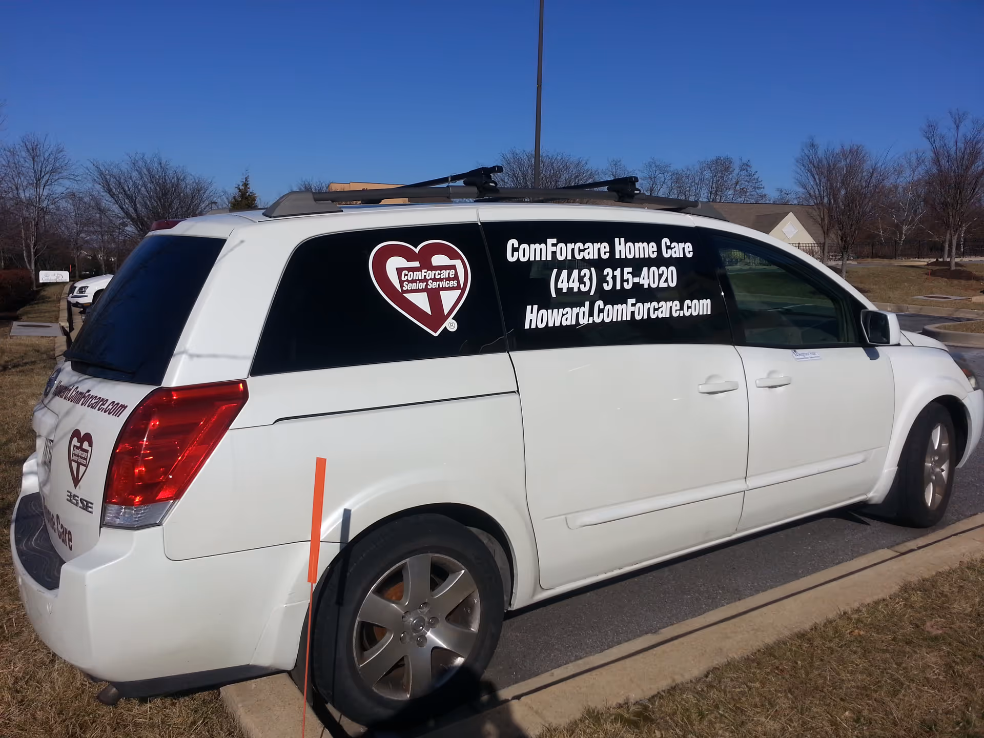 White ComForCare van parked outdoors with logo and contact info on window