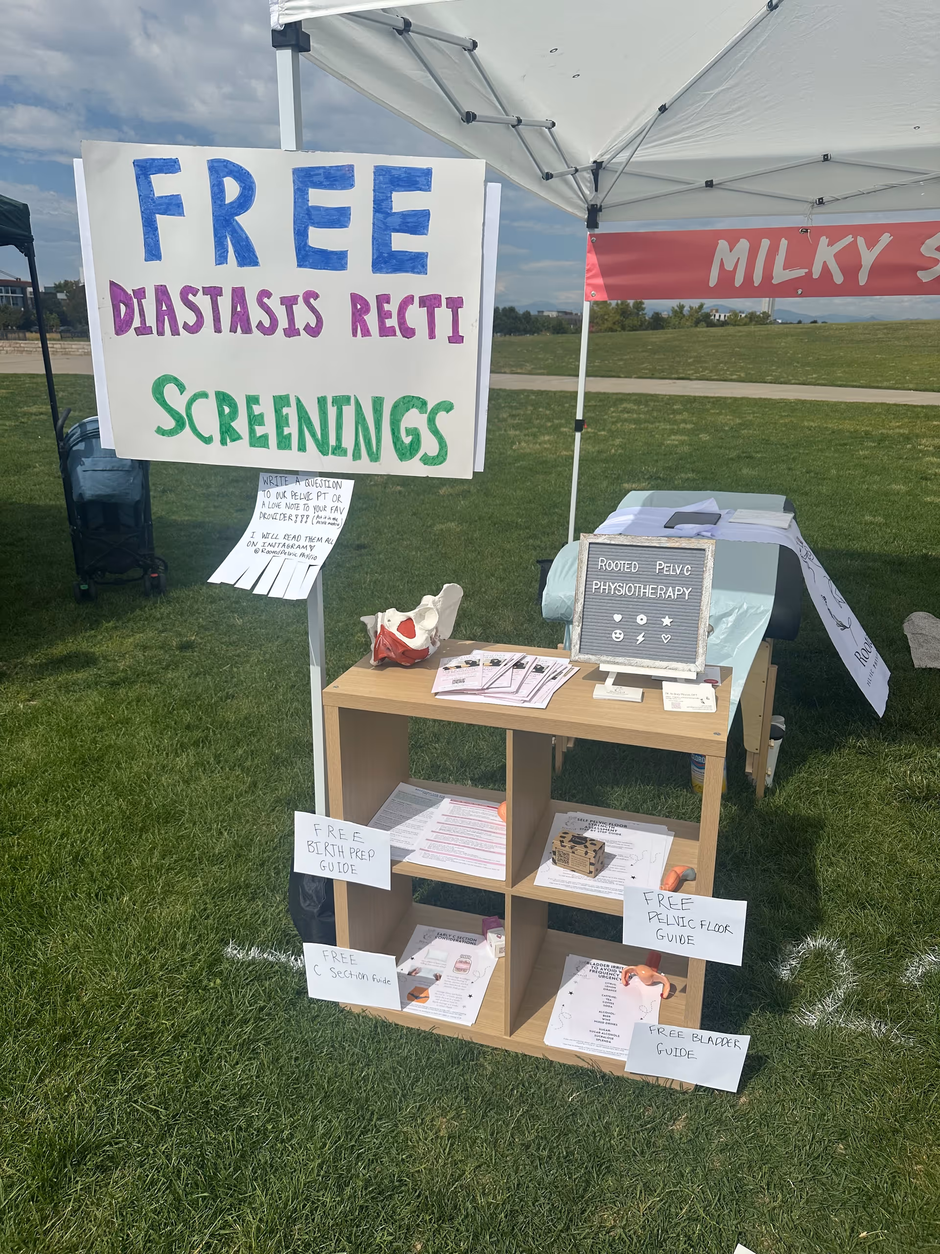 An outdoor information tent with signs offering free pelvic screenings and pamphlets.
