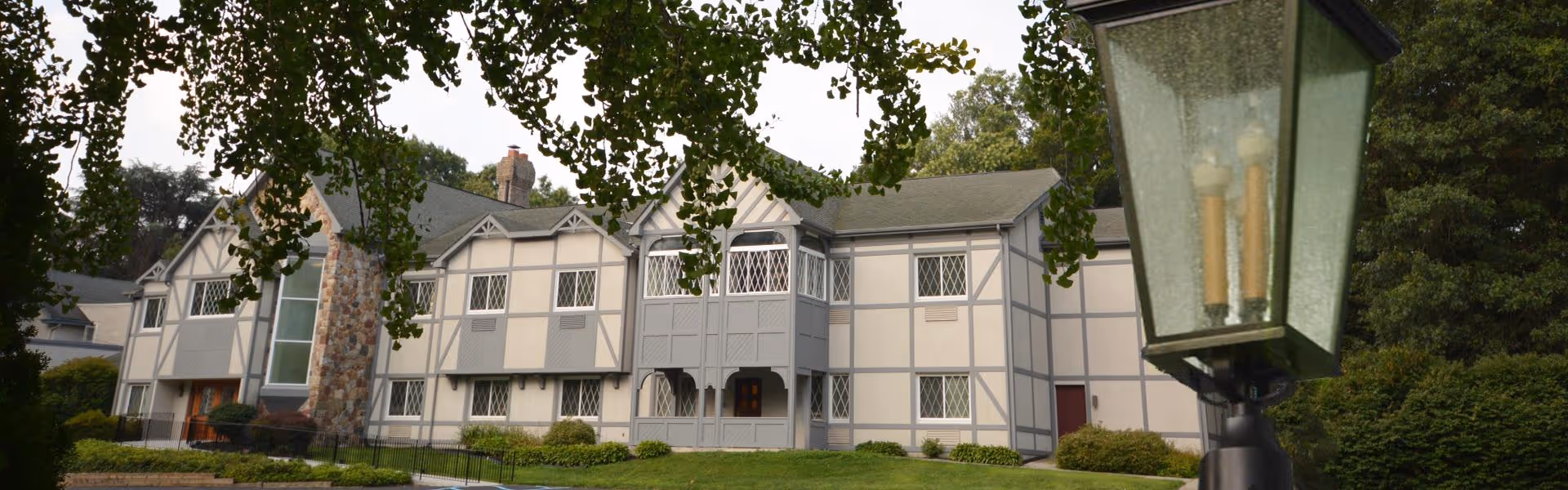Exterior view of Ivy Gables Senior Living building with a lamp post and trees.