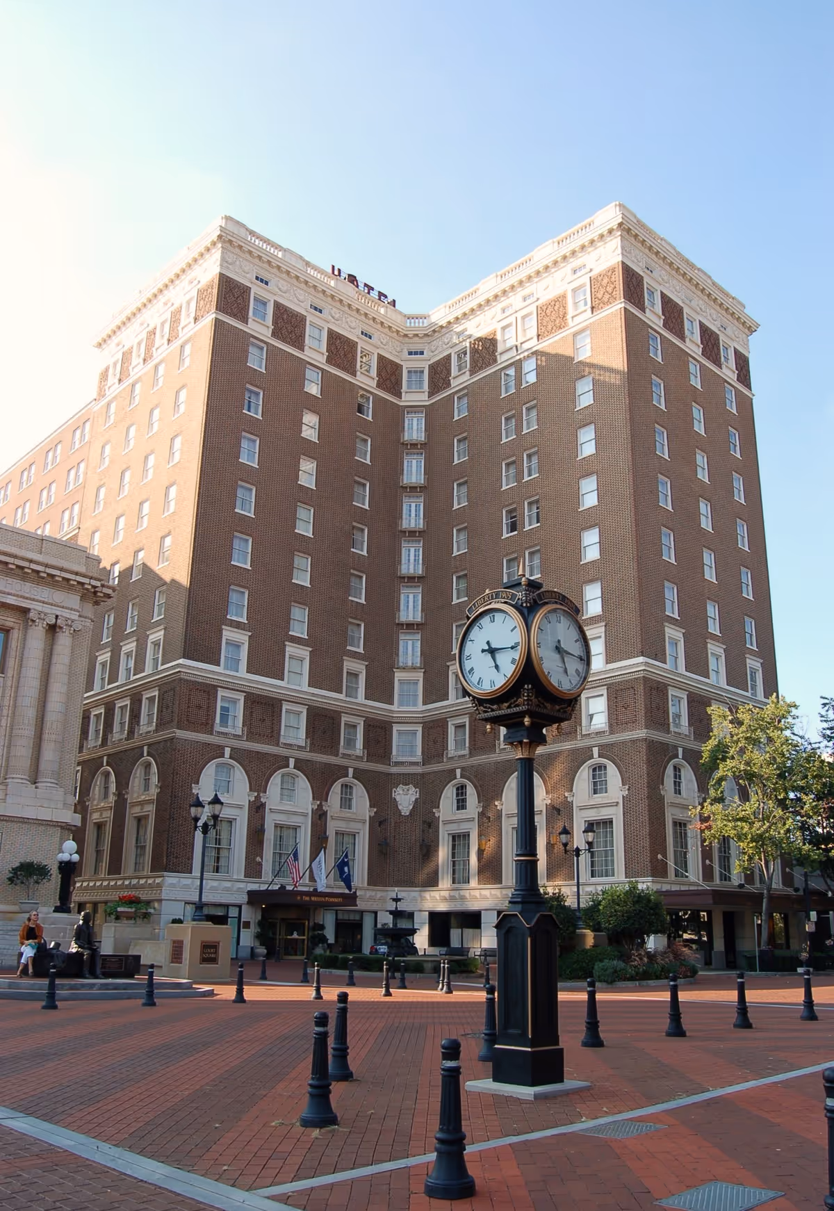 Tall brick building with a decorative clock in a brick plaza.