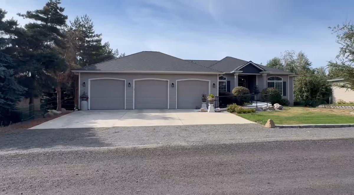 Front view of a single-story home with a three-car garage and landscaped yard.