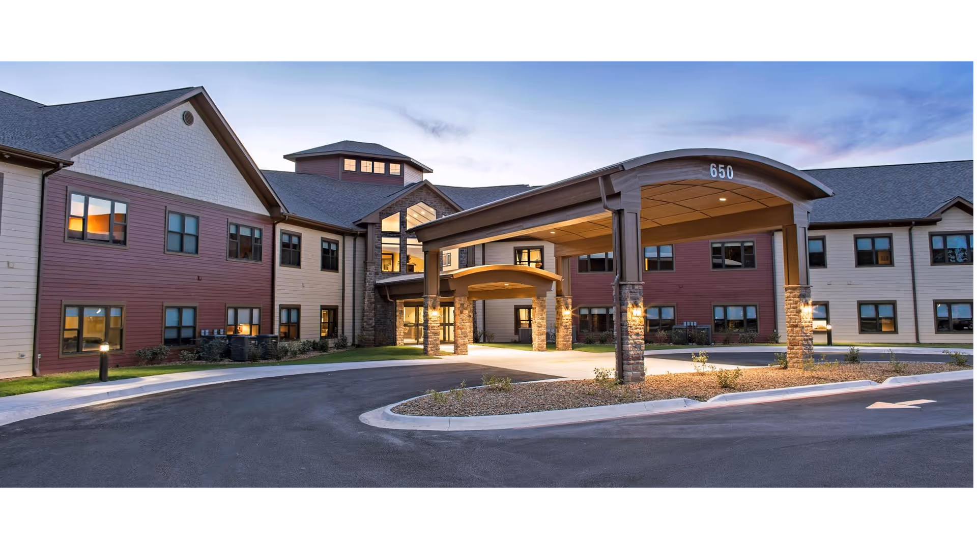 Exterior view of Primrose Retirement Community of Rogers with a covered entrance and parking.