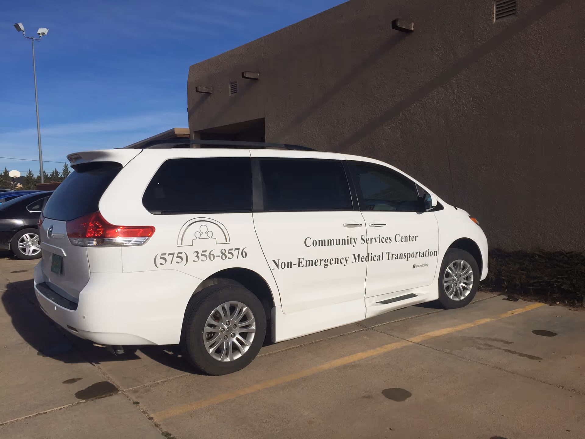 White van with Community Services Center branding parked beside a beige building.