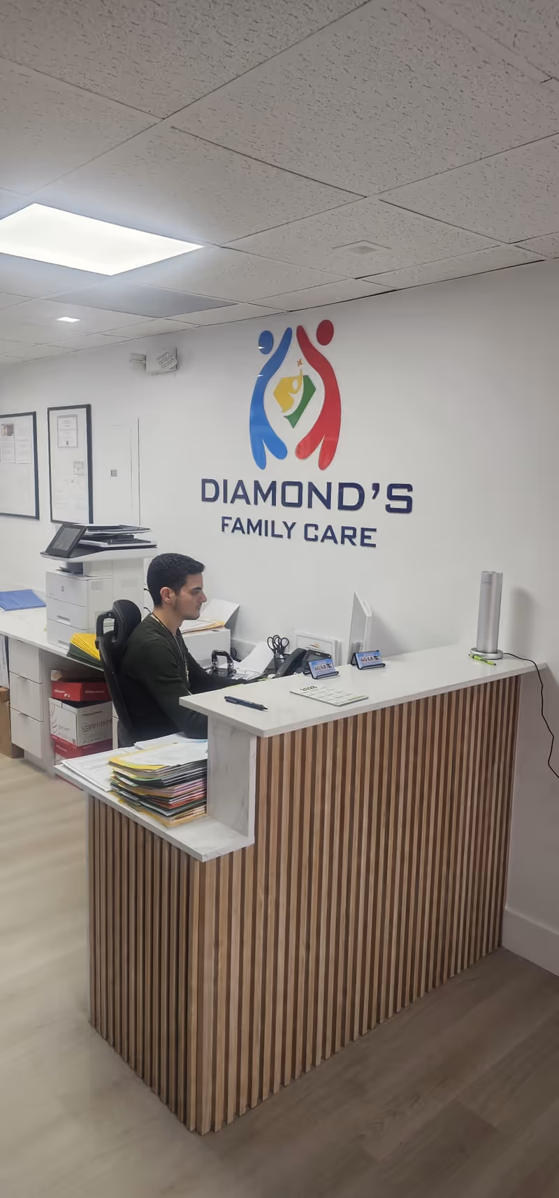 Reception desk with staff member and Diamond's Family Care sign on the wall.