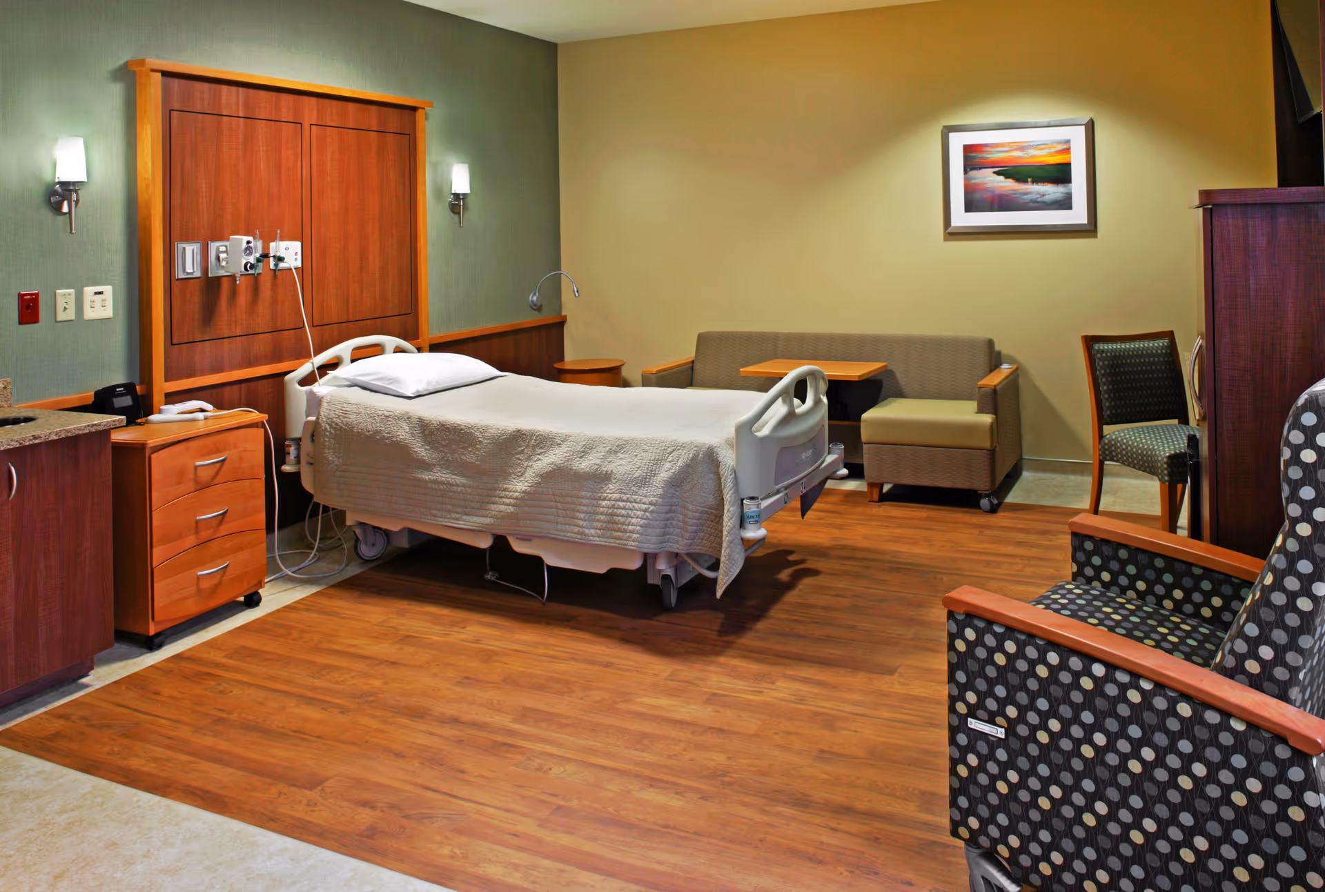 Hospice patient room at Community Hospice with hospital bed, seating area, and warm lighting.